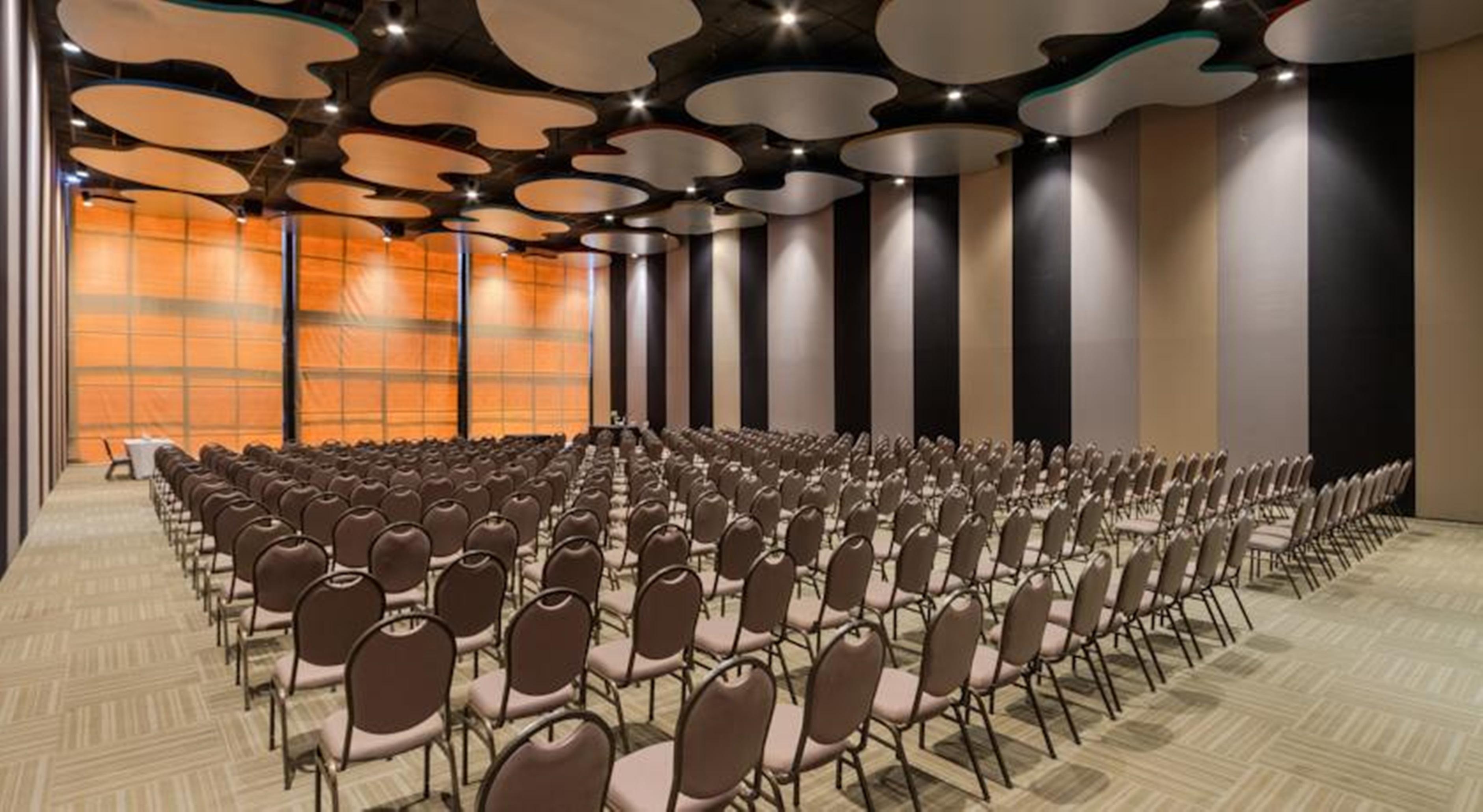 Royal Tulip Brasilia Alvorada Hotel Kültér fotó The photo shows a large conference or event space filled with numerous empty chairs arranged in rows. The chairs have a simple design, with cushioned seats and backs. The walls of the room are decorated with a combination of dark and light tones, and
