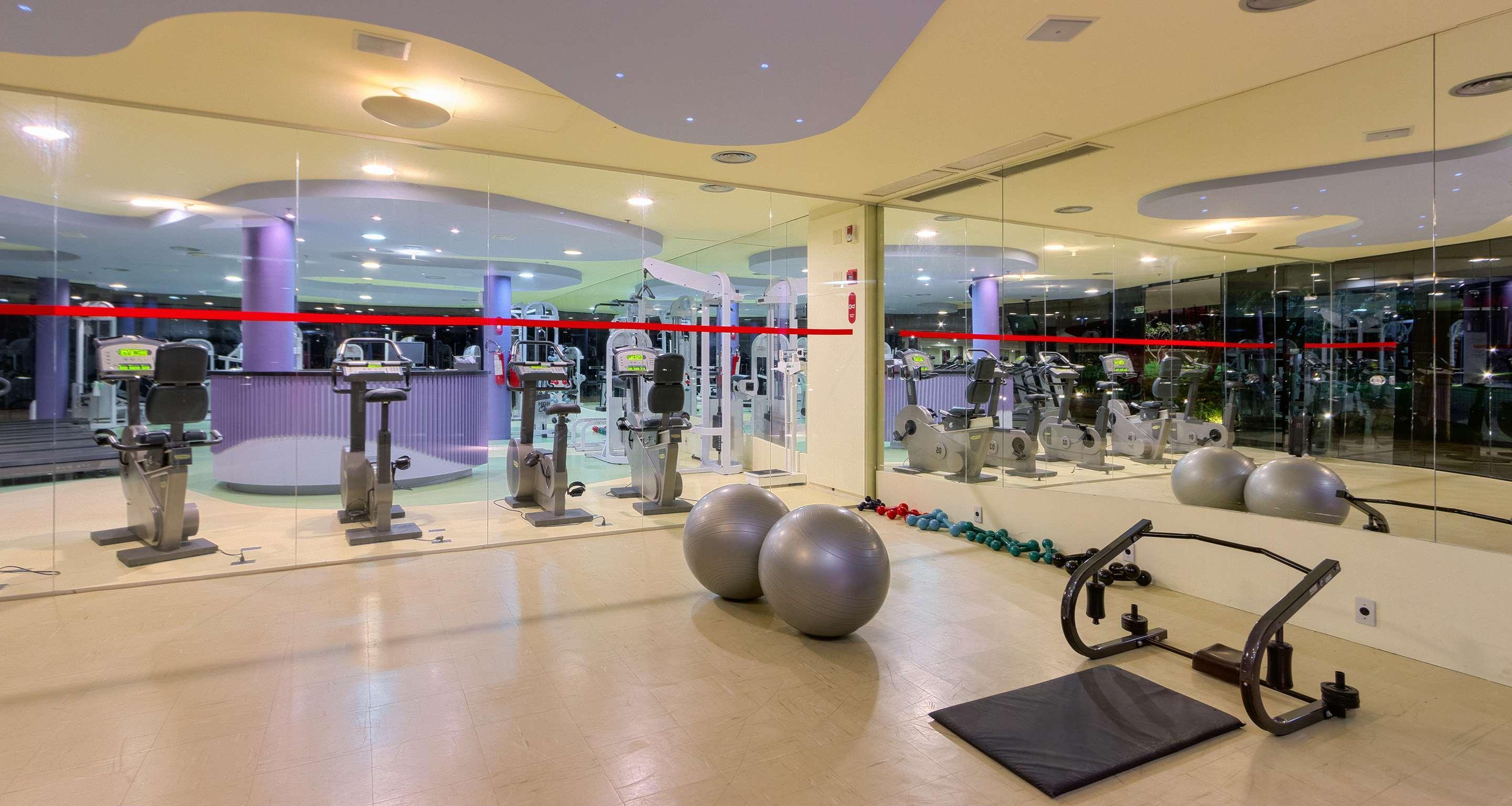 Royal Tulip Brasilia Alvorada Hotel Kültér fotó The photo depicts a gym or fitness area. In the foreground, there are two large exercise balls and a mat on the floor. Behind them, there is a wall of mirrors that reflects various gym equipment, including exercise machines and bikes. The lighting in